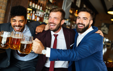 Men fans screaming and watching football on TV and drink beer in a pub