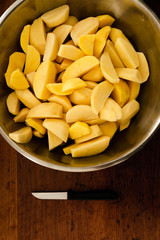 seasoned raw chopped potatoes,bowl of raw potatoes standing on the table,peeling potatoes for cooking,cooking baked potatoes,hand sprinkles seasoning in potatoes