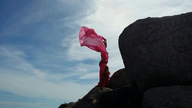 Low Angle View Of Woman Dancing On Cliff Against Sky