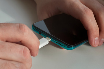 Man hands plugging a charger on a smart phone