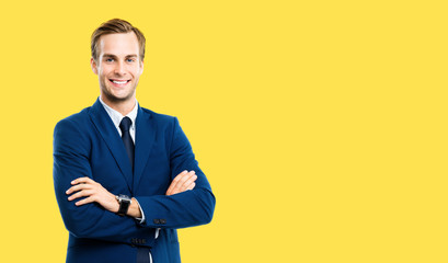 Fototapeta premium Portrait of businessman in blue suit and tie, with crossed arms, isolated against yellow background. Business success concept. Smiling man at studio picture. Copy space for some text.