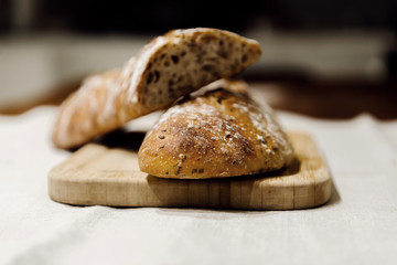 two baked homemade bread lie on the table,homemade baked bread with seeds,baguette sprinkled with flour,fresh bread on a black background,fresh bread texture