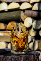 Whiskey splash in glass on a wooden background