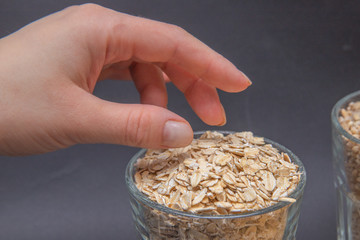 Hand reaches for dry oatmeal. Pearl barley. Vegetarian food. Source of protein and carbon dioxide. Diet. Good nutrition. Healthy food. Horizontal photo. Side view.