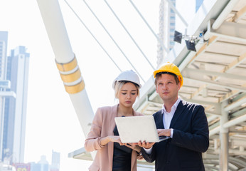 A male engineer wearing a helmet and a businesswoman Caucasoid consulted about the Blueprint building. They wanted to build an office in the middle of the city. Business cooperation concept