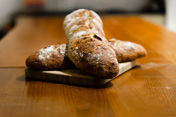 home baked fresh bread lying on a wooden table,two breads lie on a cutting board,branded home-baked bread,baguette with seeds,bran loaf