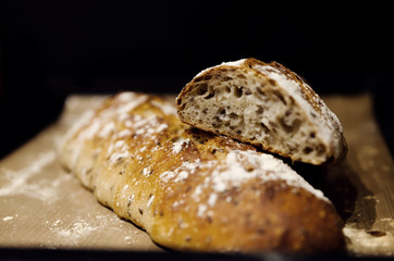two baked homemade bread lie on the table,homemade baked bread with seeds,baguette sprinkled with...