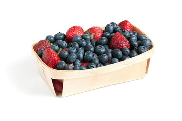Wild strawberries and blueberries in wooden box isolated on white background.