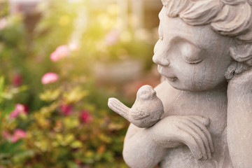 Obraz premium Boy with bird sculpture over blurred garden background, outdoor day light