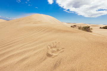 Unrecognizable hand shape in the desert. Warm weather in summer holidays. Travel to Canary Islands concept. Maspalomas natural dry dunes landscape. Spring vacations in spanish destination.