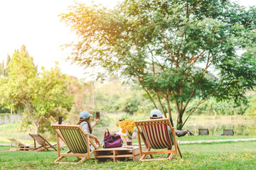 Happiness couple on a summer holiday sitting on  garden chairs to relax in the public park.