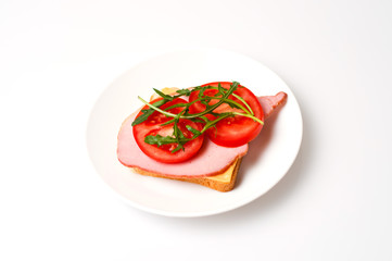 Sandwich of balyk, cheese, bread, tomatoes and arugula on a white plate on a plate