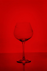 Fototapeta na wymiar Clear empty wine glass isolated on red