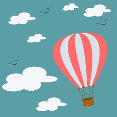 A red and white balloon flies in the sky with birds flying near the clouds