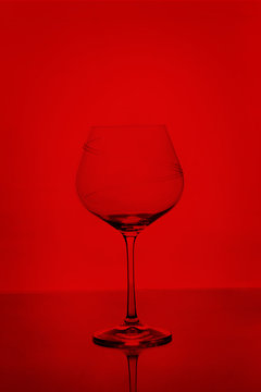 Clear empty wine glass isolated on red