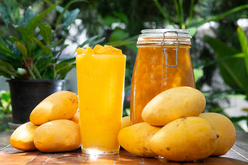 yellow mango and frappe with jam in big jar on wood table on green background stock photo