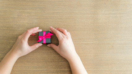 Mains touchant un cadeau sur une table en bois