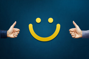 Hand of client show thumb up with smiley face card. Service rating, satisfaction concept