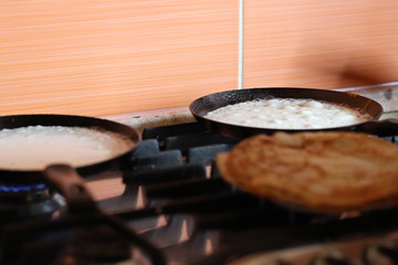 Obraz premium we fry pancakes in two pans at once, home-cooked food on Sunday morning for the family, we eat at home