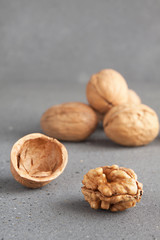 Walnuts peeled and whole in the shell on a gray background