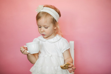 cute girl has breakfast, eats cookies and drinks kefir from a cup