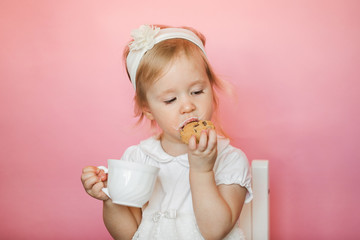 cute girl has breakfast, eats cookies and drinks kefir from a cup