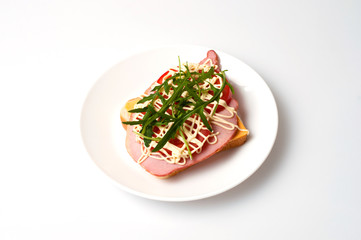 Sandwich of bread for toast, sturgeon, tomatoes, arugula, cheese and mayonnaise on a white plate in the view from the top flat lay