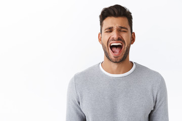 Close-up whining cute bearded hispanic guy screaming from pain or depression, losing temper hate being surrounded problems, shouting out loud, open mouth wide while eyes close, white background