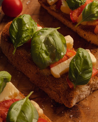 toast bread with mozzarella basil and cherry tomatoes on wooden background