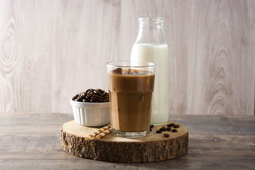 Iced coffee or caffe latte in tall glass on wooden table. 