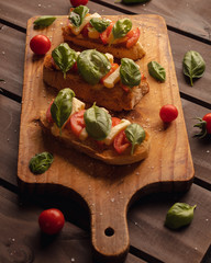 toast bread with mozzarella basil and cherry tomatoes on wooden background