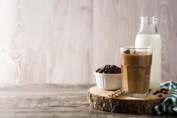 Iced coffee or caffe latte in tall glass on wooden table. Copy space