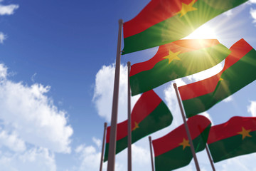 Burkina Faso flags waving in the wind against a blue sky. 3D Rendering