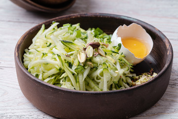 Ingredients for zucchini fritters,  freshly grated zucchini, egg yolk, pistachios and seasoning