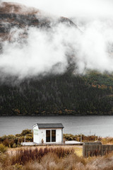 Single House Isolated in the middle of the Mountains with fog rolling through over the lake