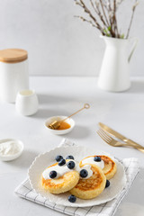 Cottage cheese pancakes with fresh blueberries and sour cream. Russian syrniki or sirniki, cottage cheese fritters or pancakes served with berries. Restaurant menu, cookbook recipe