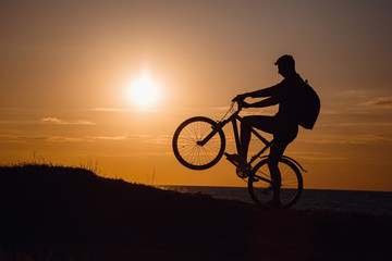 Obraz premium Silhouette of cyclist in motion at beautiful sunset.