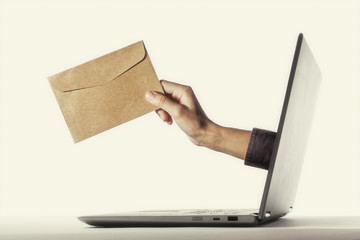 The human hand with envelope stick out of a laptop screen. Concept of correspondence, feedback,...