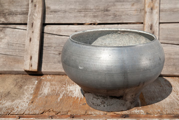 a large cast-iron cauldron of metallic color stands on a wooden background, a pot open