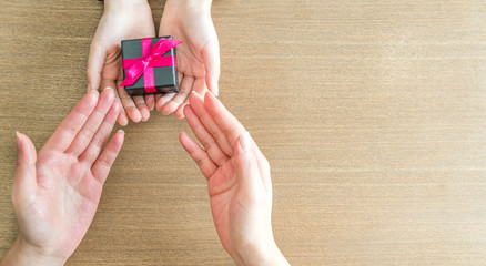 Mains s'échangeant un cadeau sur une table en bois 