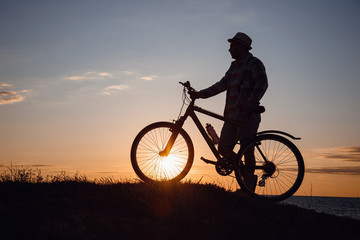 Fototapeta na wymiar silhouette of a hipster man on a bicycle on sunset background