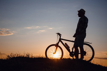 Obraz premium silhouette of a hipster man on a bicycle on sunset background