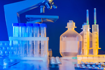 Empty test tubes next to microscope. Plastic test tubes with a cap. Concept - disposable tableware for the lab. Concept - the fight against the epidemic. Different medicines on the table researcher