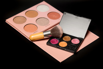 Color palette of eye shadows and brushes for professional make-up artist on a black background