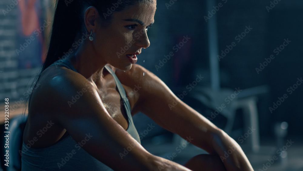 Wall mural beautiful strong fit brunette in sport top and shorts in a loft industrial gym with motivational pos