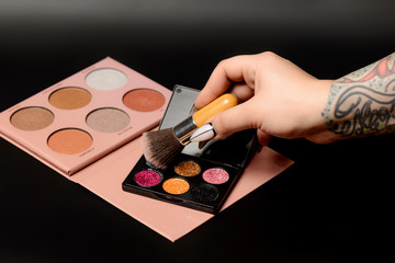 Color palette of eye shadows and brushes for professional make-up artist on a black background