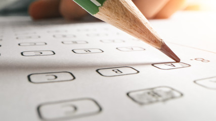 On Exam Test Person Colors Right Answers with a Pencil. Filling up Answer Sheet with Standardized...