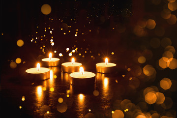 Several burning candles with festive bokeh on a black background.