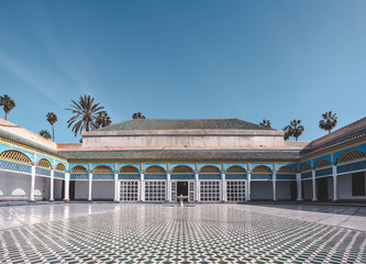 Obraz premium View to empty Courtyard and colorful traditional arabic patio at El Bahia Palace, Marrakech, Morocco. Travel concept photo on a sunny day with blue sky and no clouds. Palm trees in background.