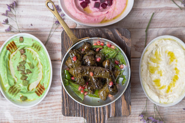 Stuffed grape leaves on wooden desk with hummus variations